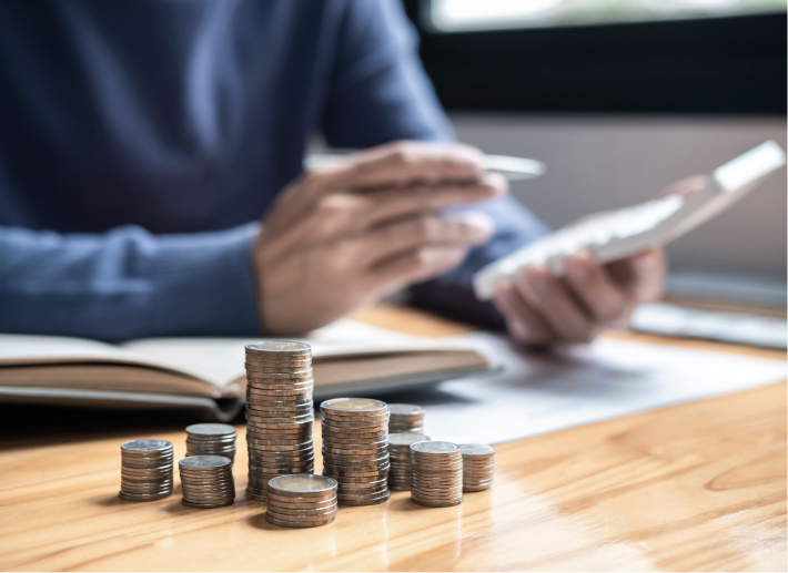 Stacked coins on the table with a man reading
